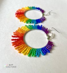 two pairs of colorful beaded hoop earrings on white surface with silver earwires