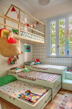 a child's bedroom with bunk beds and toys on the bottom bed, in front of a window