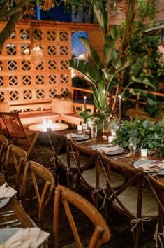 an outdoor dining area with wooden chairs and tables set up for a meal, surrounded by greenery