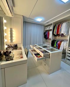 a closet with drawers, lights and clothes on the shelves is shown in this image