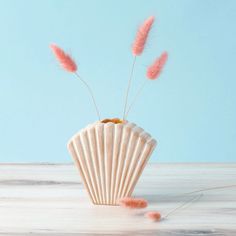 some pink feathers are sticking out of a cupcake shaped object on a white table