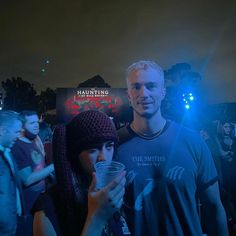 a man and woman standing next to each other in front of a crowd at night