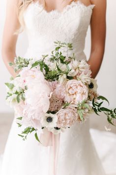 a bride holding a bouquet of pink and white flowers