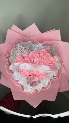 a bouquet of pink roses in a heart - shaped box with a ribbon on it