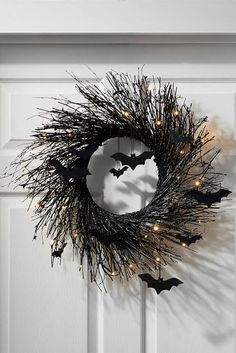 a halloween wreath with bats hanging from it's side and lights on the front door