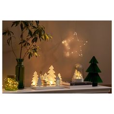 christmas decorations are displayed on a shelf in front of a tree and snow globes