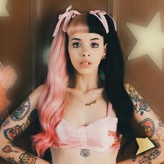 a woman with pink hair and tattoos standing in front of a door wearing a bra