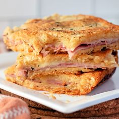 two ham and cheese sandwiches stacked on top of each other in front of some bread