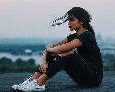 a woman sitting on the ground with her legs crossed