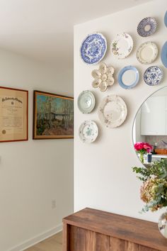 plates are arranged on the wall above a dresser