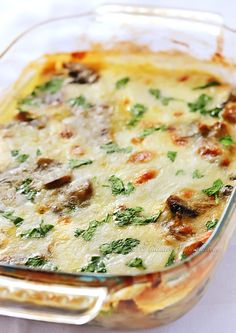 a casserole dish with cheese and vegetables in it on a white tablecloth