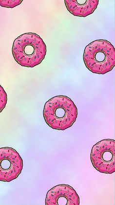 several pink donuts with sprinkles on a pastel colored background,