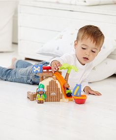 a little boy playing with his toy pirate ship set on the floor in front of him