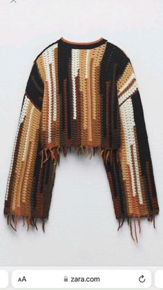 a knitted sweater with fringes on the front and back, sitting on top of a white surface