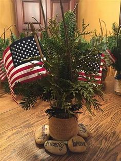 a potted plant sitting on top of a wooden table next to two american flags