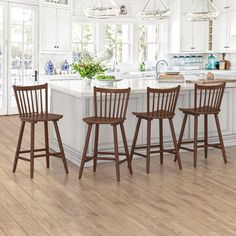 a kitchen with white cabinets and wooden chairs in front of an island that has four stools on it