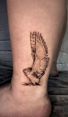 a small bird tattoo on the side of a woman's leg, it is black and white