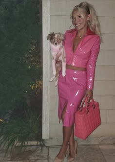 a woman in a pink outfit holding a small dog