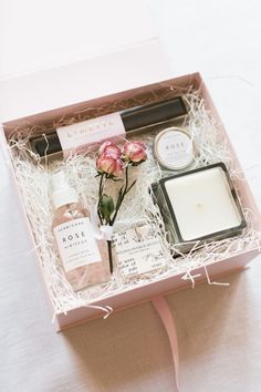 a pink box with flowers, candles and personal care items