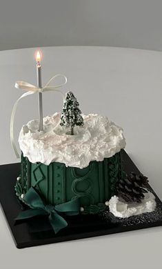 a green cake with white frosting and a lit candle