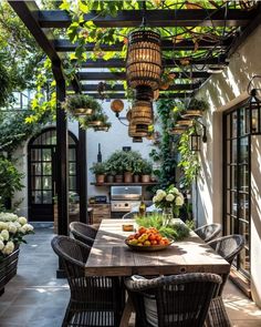 an outdoor dining area with potted plants on the table and hanging lights above it