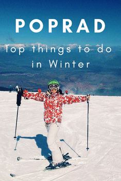 a person on skis standing in the snow with their arms spread out and smiling