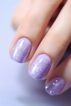 a woman's hand with purple nail polish and glitters on it, holding onto her nails