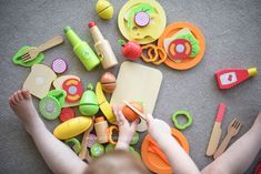 a child is playing with toys on the floor, including utensils and cutting boards