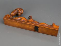 a wooden carved figurine laying on top of a piece of wood