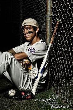 a baseball player poses with his bat in front of a chain link fence at night