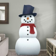 a snowman with a hat and scarf on standing in front of a living room