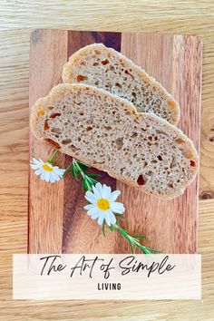 two slices of bread sitting on top of a wooden cutting board with daisies and the words, the art of simple living