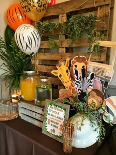 a table topped with lots of different types of decorations and balloons in front of a wooden pallet