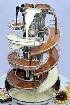 a stack of chocolate desserts with milk being poured into the cups and saucers