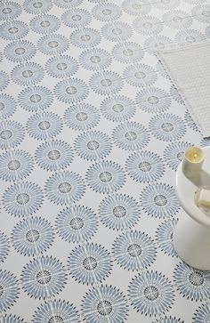 a blue and white tile floor with a vase next to it