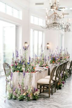 a long table with chairs and tables covered in cloths is decorated with purple flowers