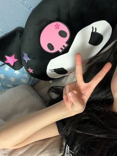 a woman laying on top of a bed next to a large stuffed animal head with pink eyes