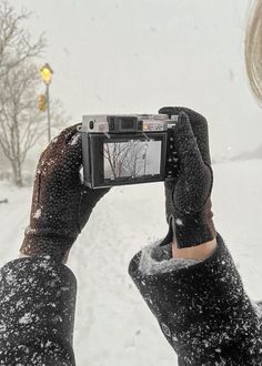 a person holding up a camera to take a photo in the snow with their hands