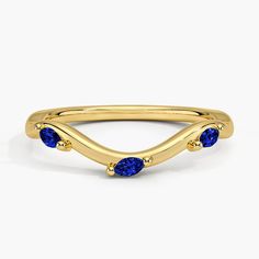 a yellow gold ring with three blue sapphire stones on the sides and an open band