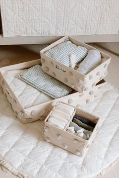 three boxes are stacked on top of each other with folded clothes in them sitting on the floor