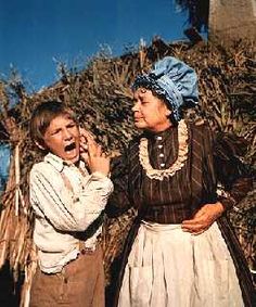 two people standing next to each other in front of some trees and bushes with one woman covering her mouth