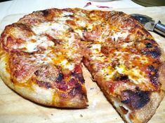 a pizza sitting on top of a wooden cutting board next to a knife and fork