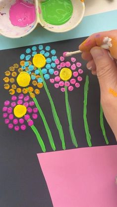 someone is painting flowers on a piece of paper