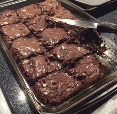 a pan filled with brownies sitting on top of a counter next to a knife