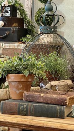 a table topped with books and plants on top of each other next to a clock