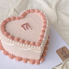 a heart - shaped cake with pearls and pink icing on a white tablecloth