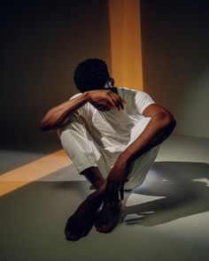 a man is sitting on the floor with his hands behind his head and legs crossed