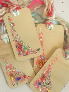 four wooden tags with colorful beaded designs on them sitting next to a white and pink scarf