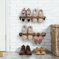 several pairs of shoes are sitting on wooden shelves in front of a white brick wall