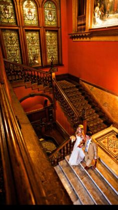 the bride and groom are walking down the stairs at their wedding ceremony in an ornate building